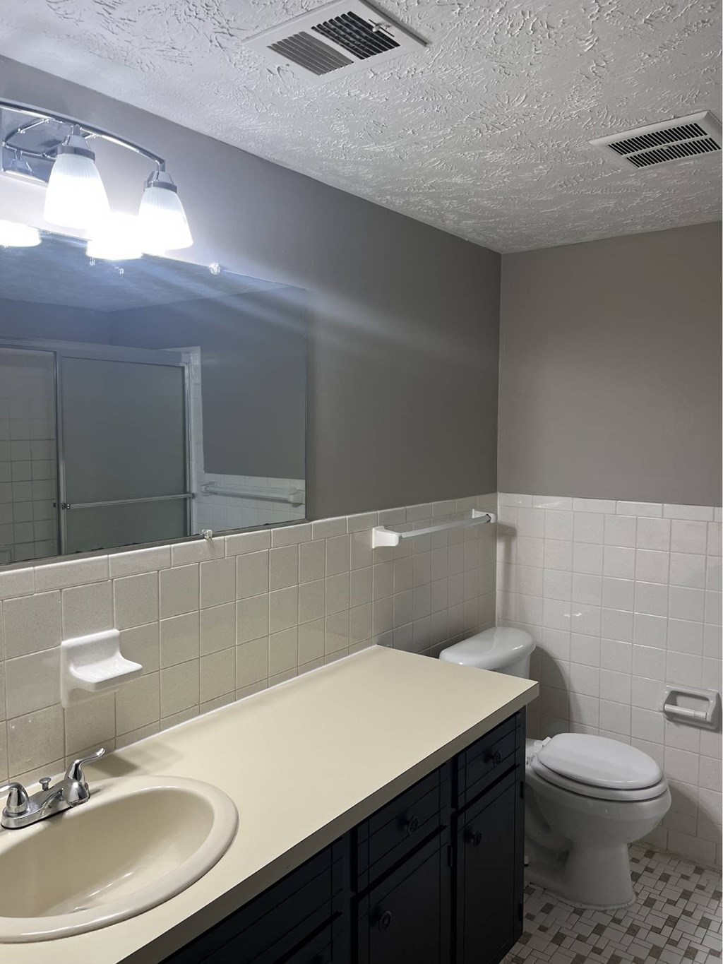 A bathroom with a toilet, sink, and mirror.