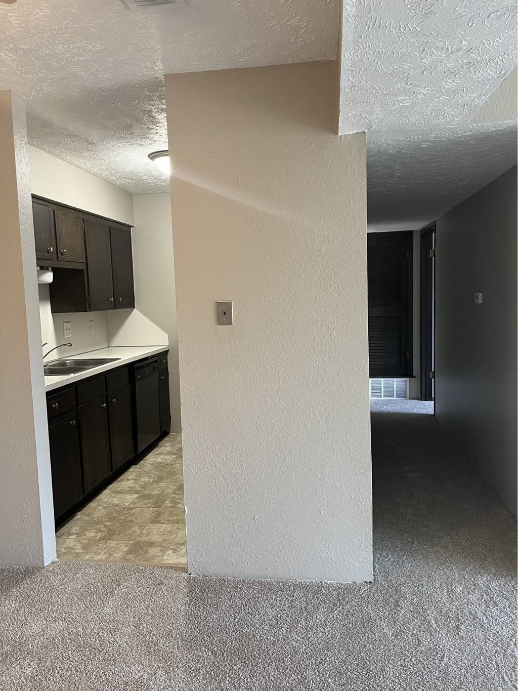 A kitchen with black cabinets and a white wall.