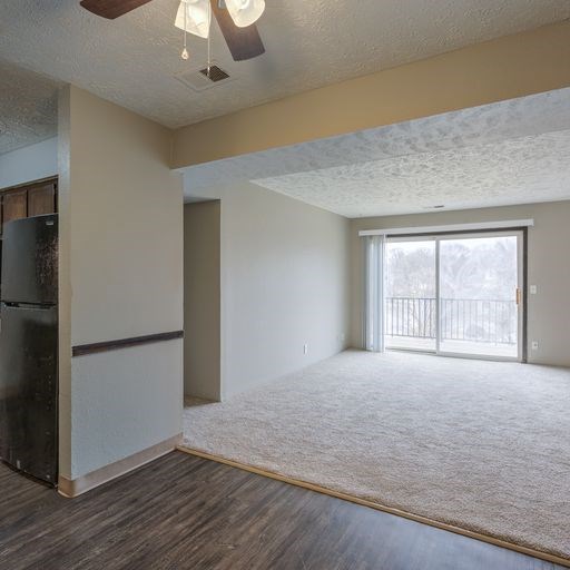 A room with a ceiling fan and a refrigerator.