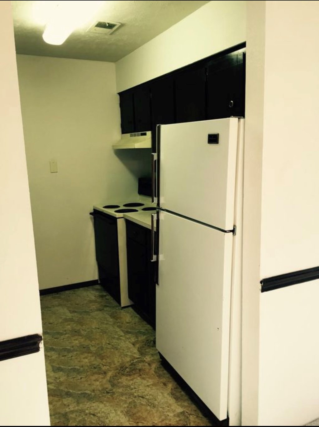 A white refrigerator in a kitchen with black cabinets.
