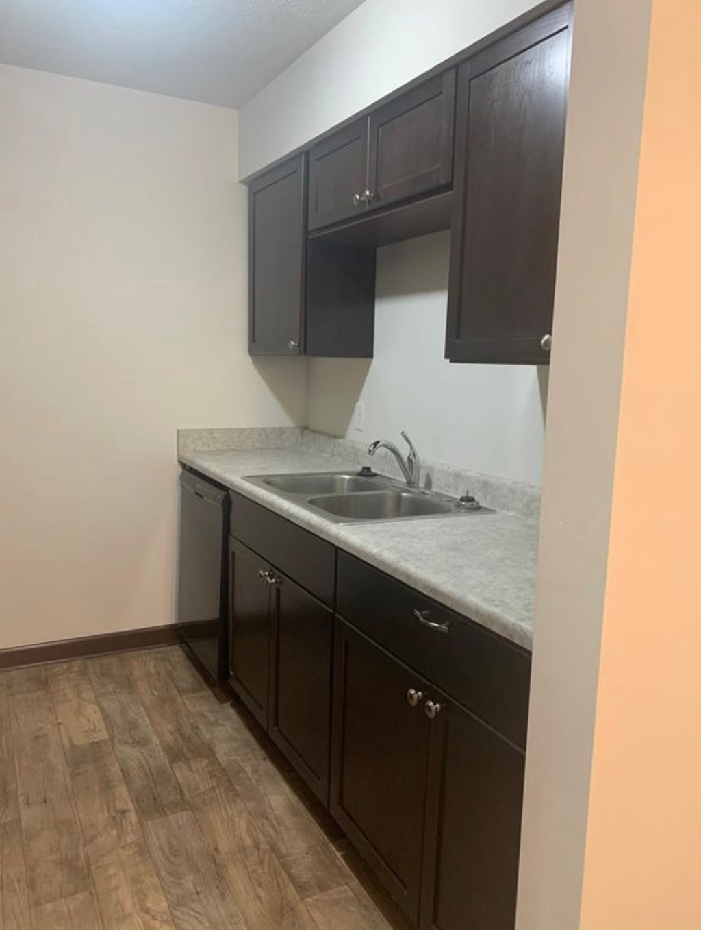 A kitchen with dark brown cabinets and a white countertop.