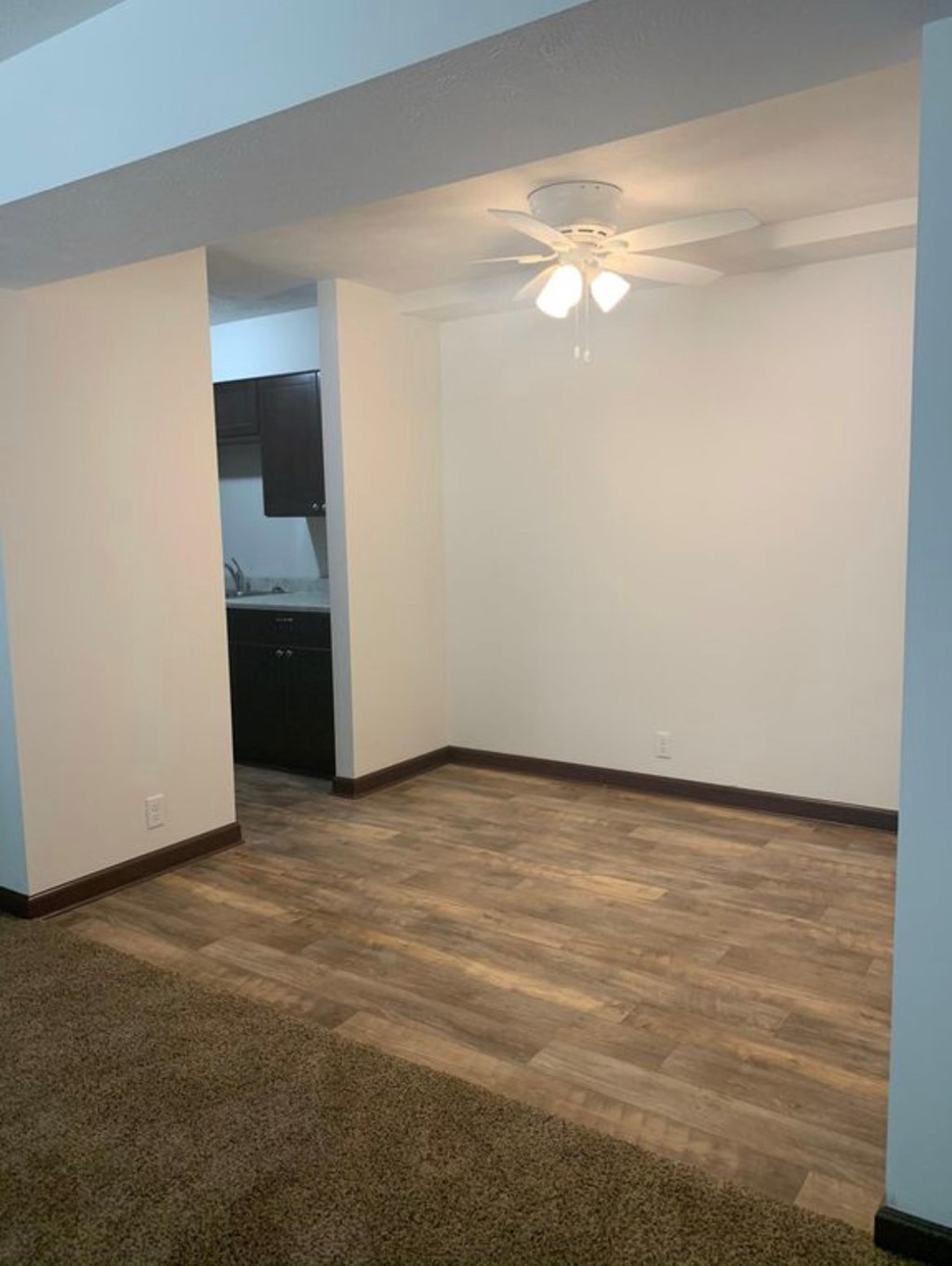 A room with a ceiling fan and a wooden floor.