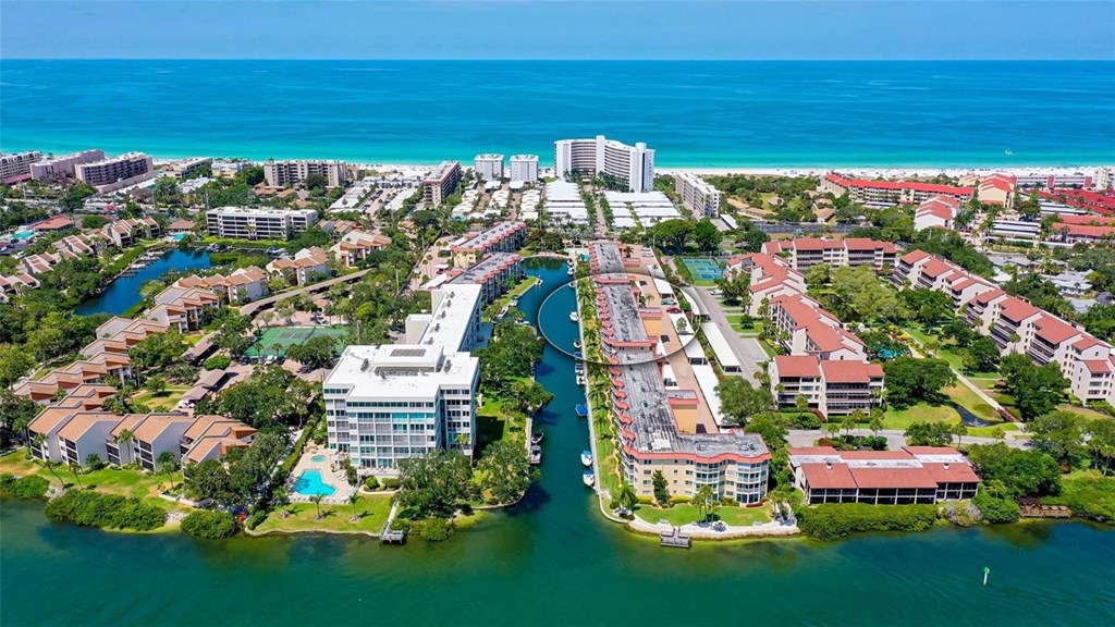 A bird's eye view of a coastal residential area with buildings surrounded by water.