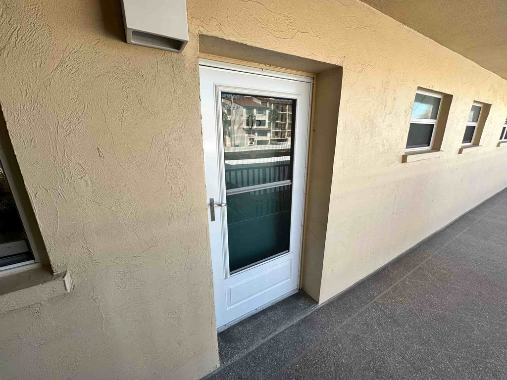 A white door with a window above it on a beige wall.