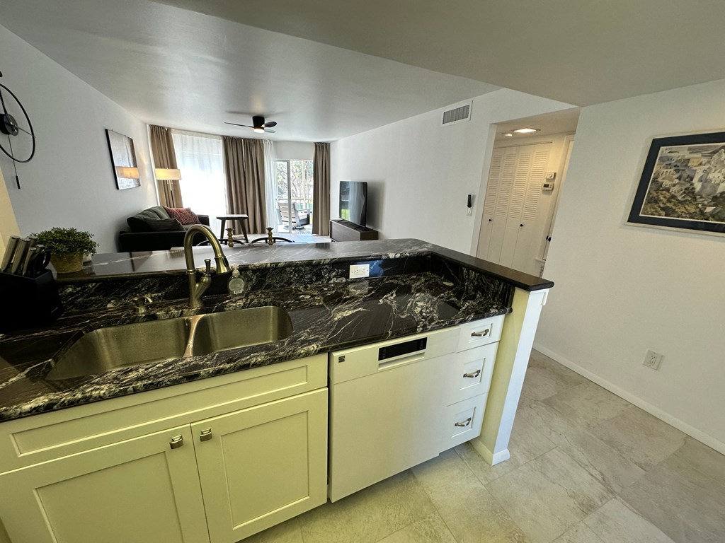 A kitchen with a marble countertop and white cabinets.