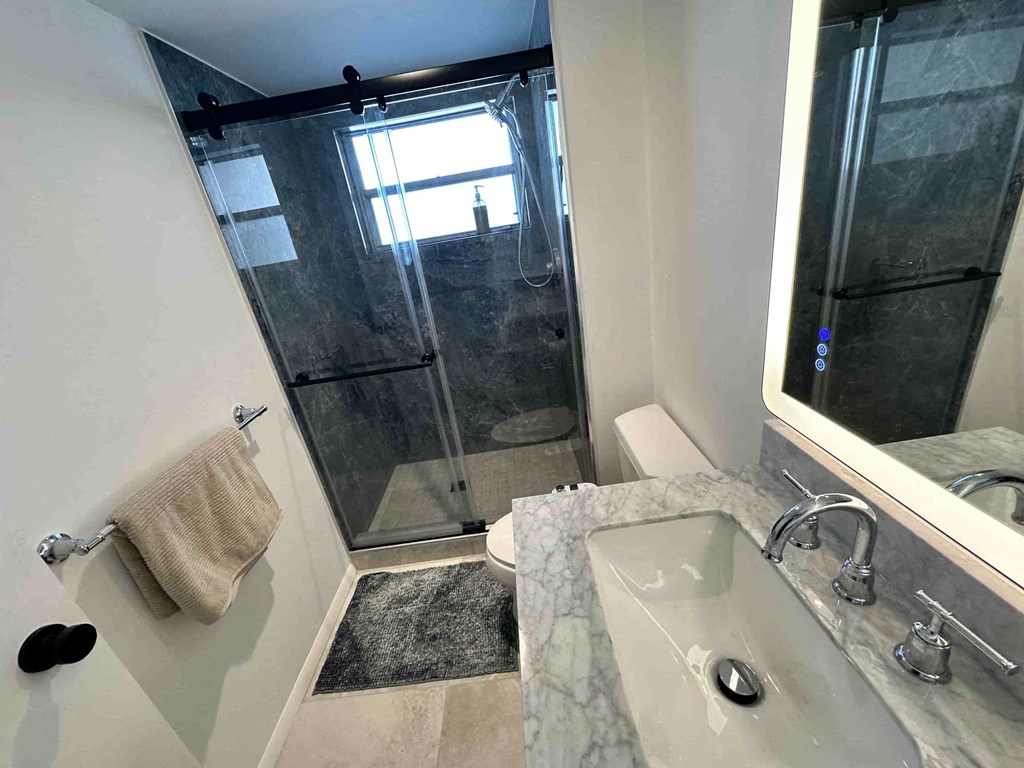 A bathroom with a marble sink and a glass shower stall.