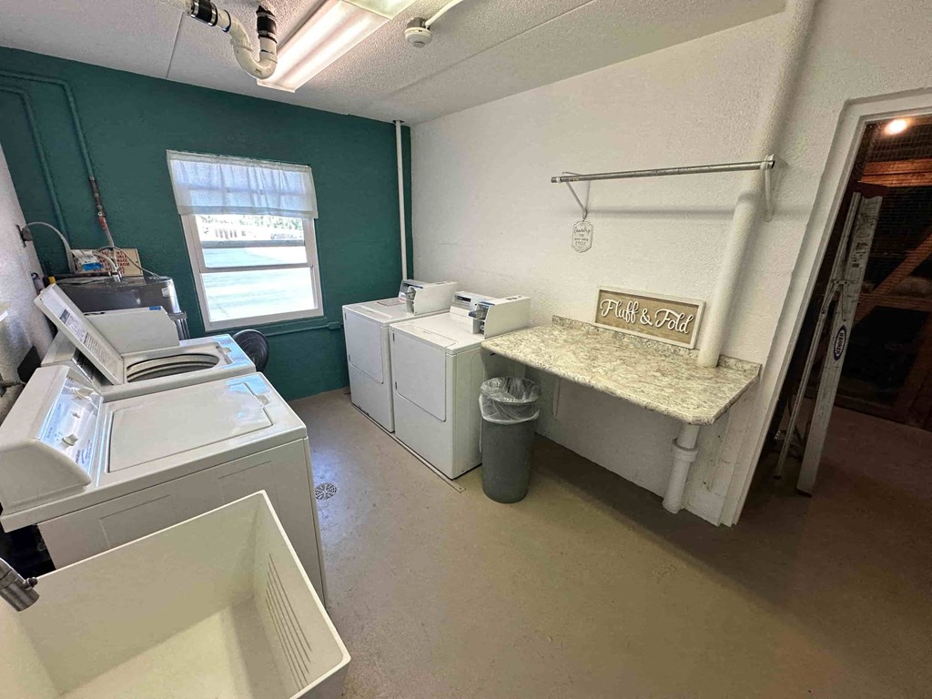 A room with a washing machine, a dryer, and a sign that says "Fresh Clean".