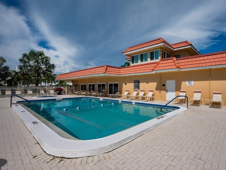 A large outdoor swimming pool with a red roofed building behind it.