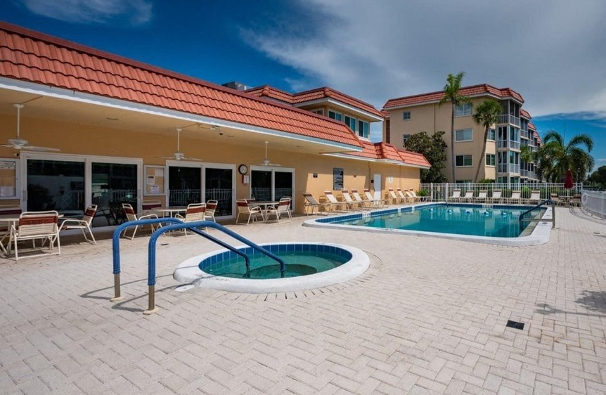 A pool with a diving board is surrounded by a brick patio.
