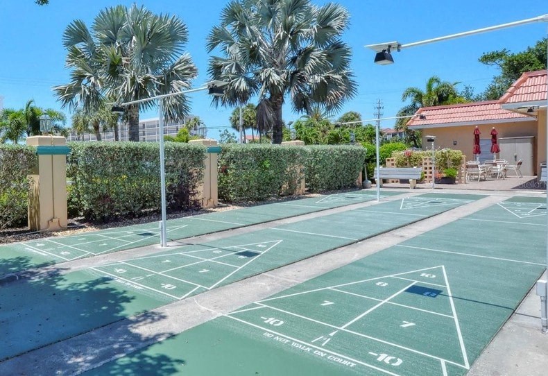 A tennis court with green markings and a white line in the middle.