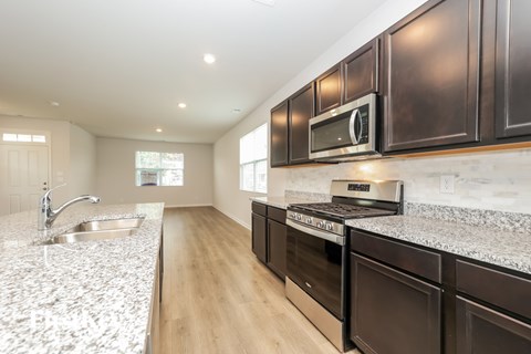 A kitchen with dark brown cabinets and a granite countertop.