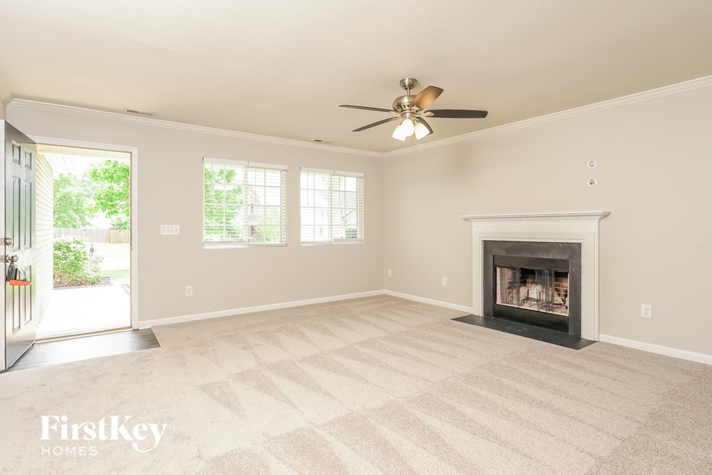 A living room with a fireplace and a ceiling fan.