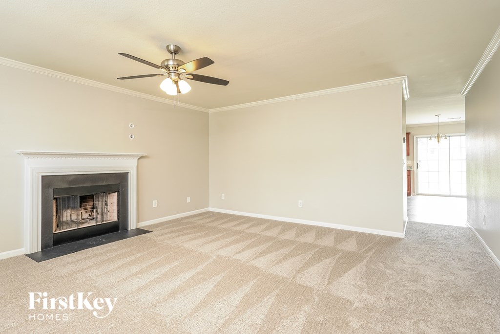 A spacious room with a fireplace and a ceiling fan.