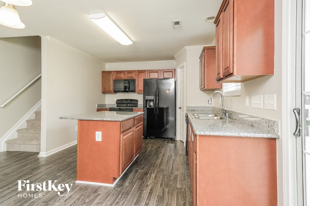 A kitchen with wooden cabinets and a black refrigerator.