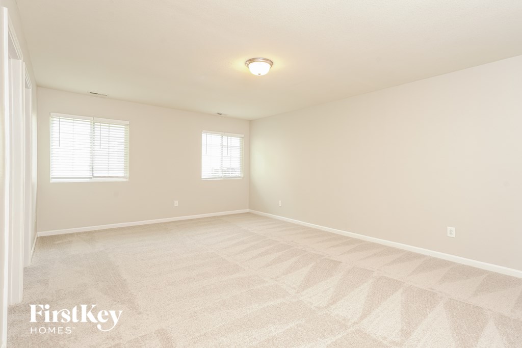 A room with a carpeted floor and two windows.