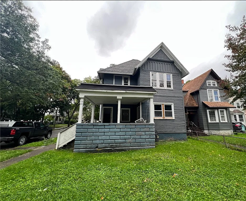 A grey house with a black truck parked in front.