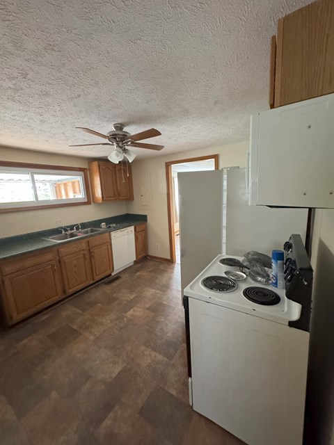 A kitchen with a white refrigerator and a white stove top oven.