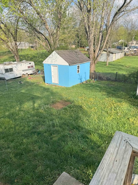 A blue shed sits in a grassy yard.