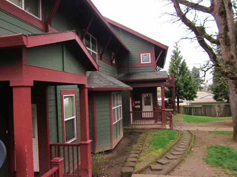 A green house with red trim and a small porch.