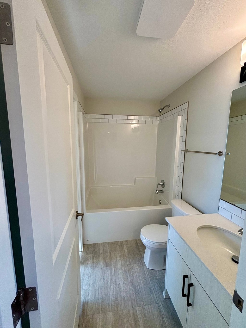 A white toilet sits in a bathroom next to a bathtub.