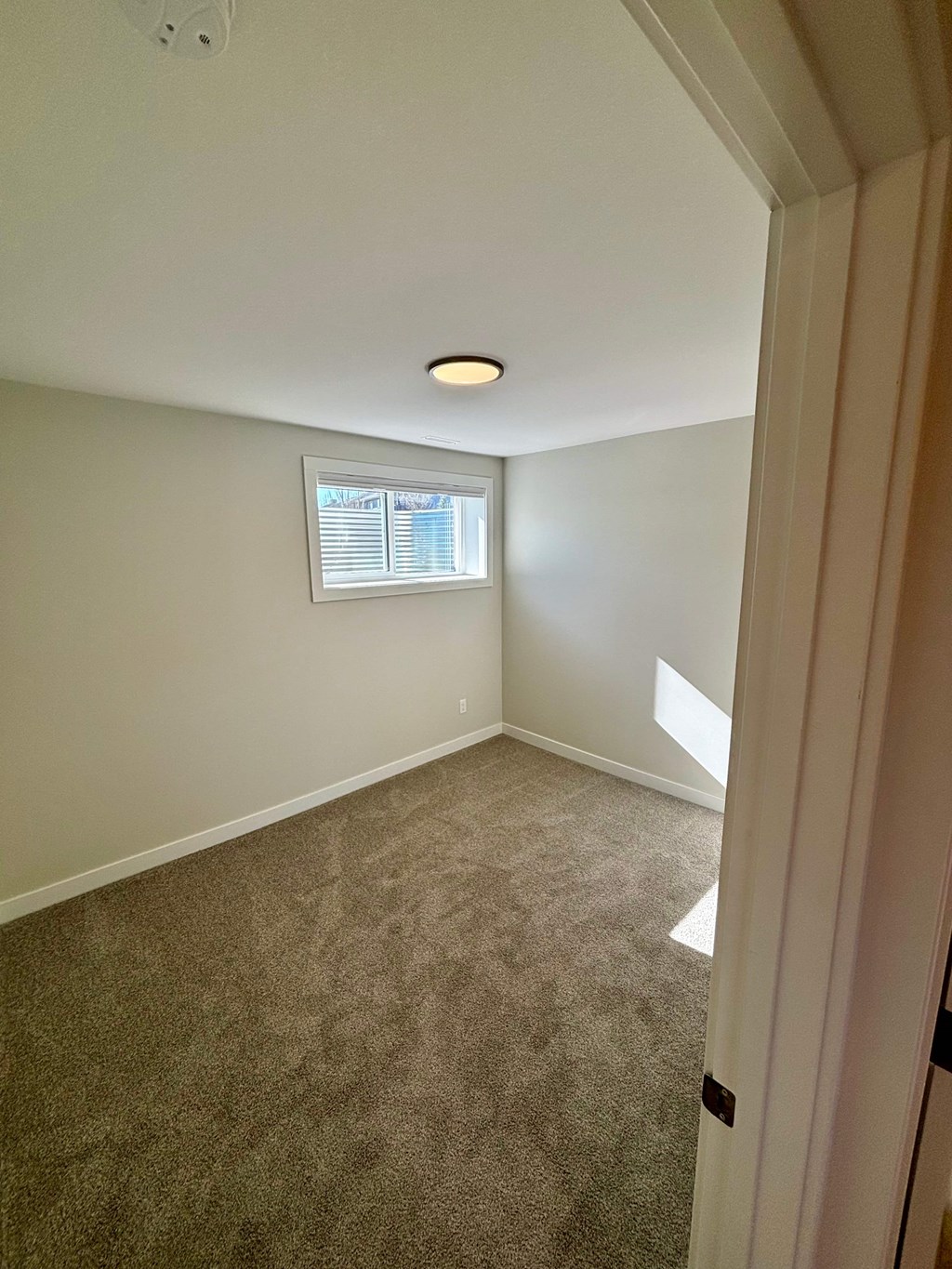 A room with a window and carpeted floor.