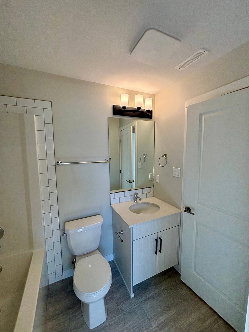 A white bathroom with a toilet, sink, and mirror.