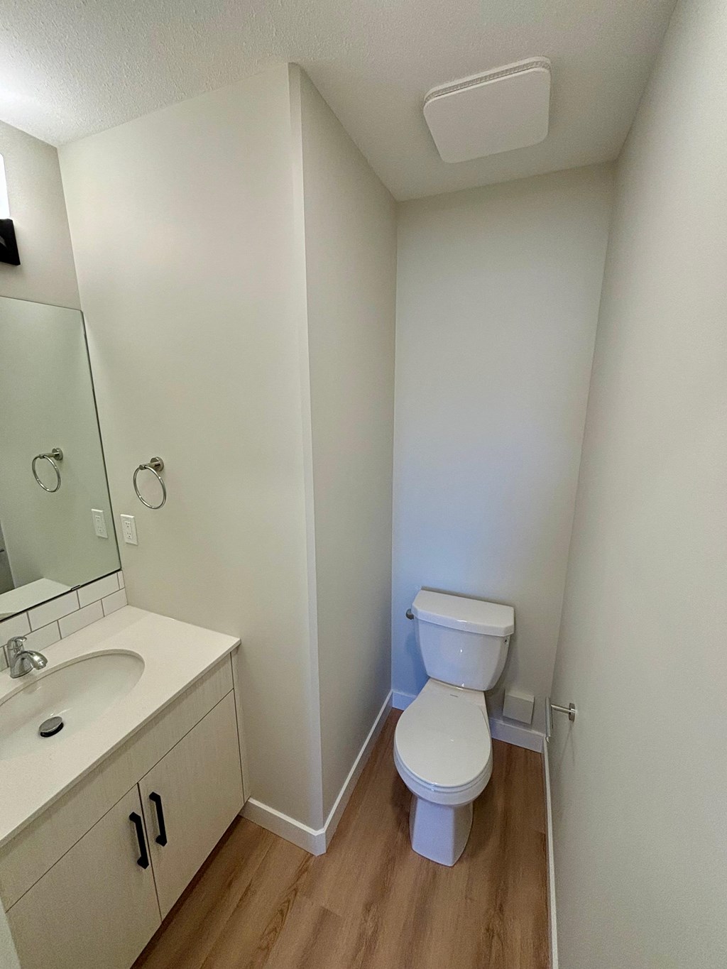 A white toilet sits in a small bathroom next to a sink.