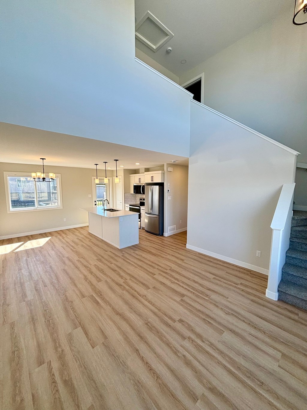 A kitchen with white cabinets and a refrigerator is visible through a glass door.