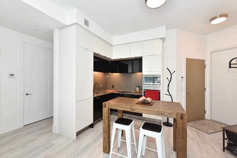 A modern kitchen with a wooden table and bar stools.