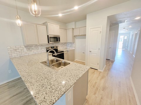 A kitchen with a granite countertop and white cabinets.