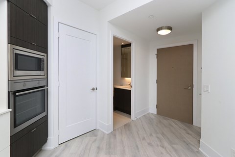 A kitchen with a white door and a microwave above the oven.
