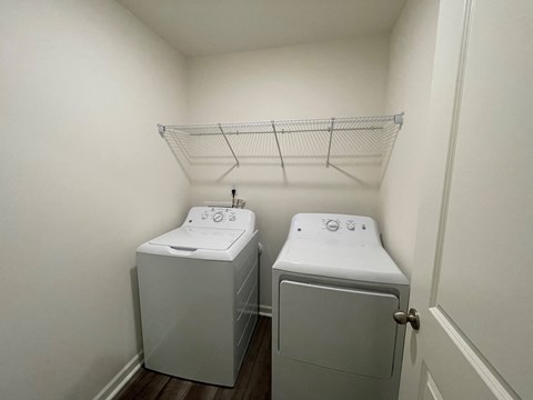 Two white washing machines in a small laundry room.