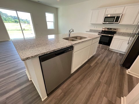 A kitchen with white cabinets and a granite countertop.
