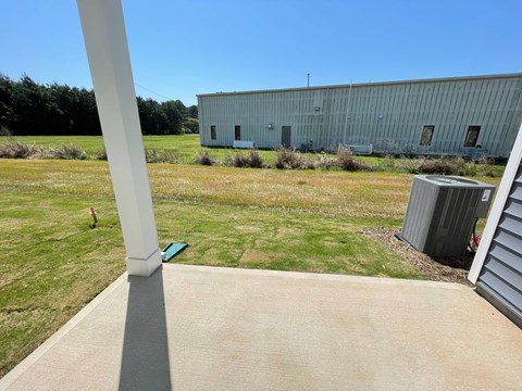 A large metal building with a grey roof is surrounded by a grassy field.