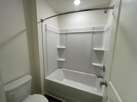 A white bathroom with a toilet, tub, and towel rack.