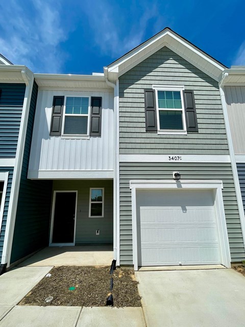 A two-story house with a garage door and a window on the front.
