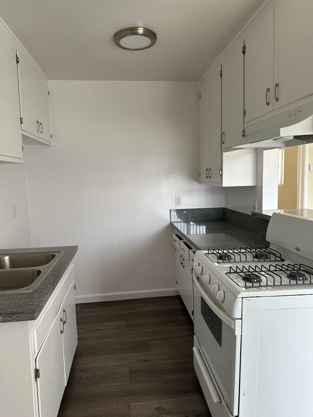 A white kitchen with a stove and sink.