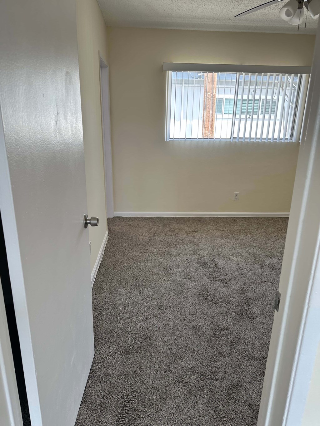 A room with a carpeted floor and a window with blinds.