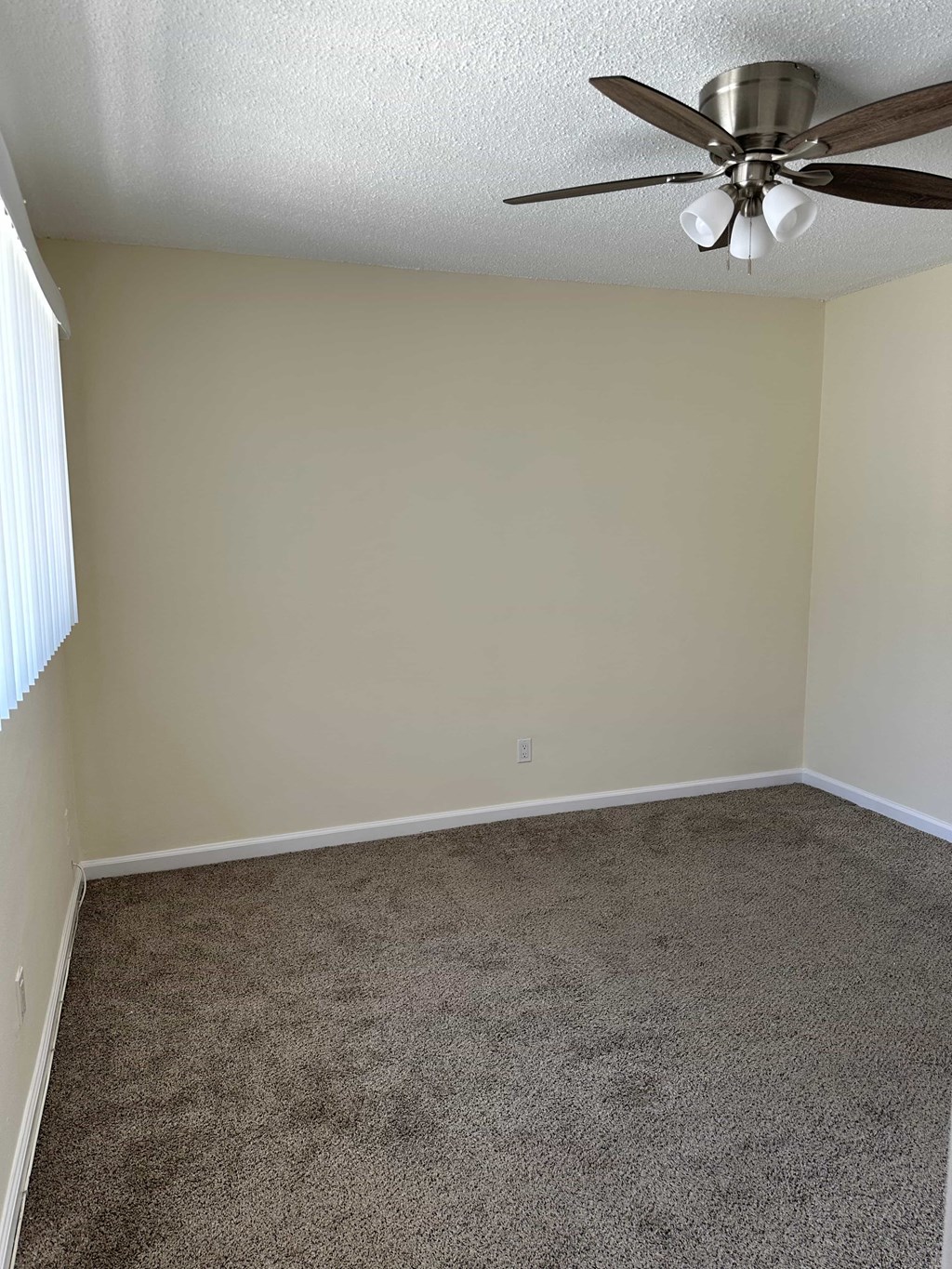 A room with a ceiling fan and carpeted floor.