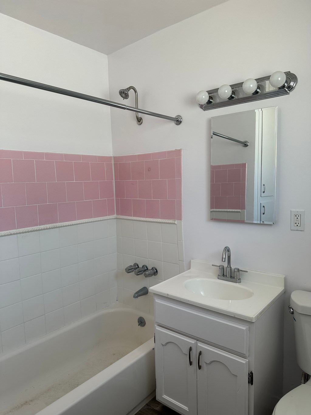 A white bathroom with pink tiles on the wall.