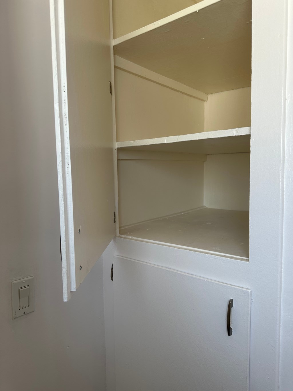 A white cabinet with a door and a handle is open.