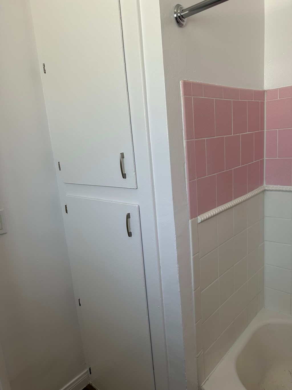 A white bathroom with a pink tile wall.