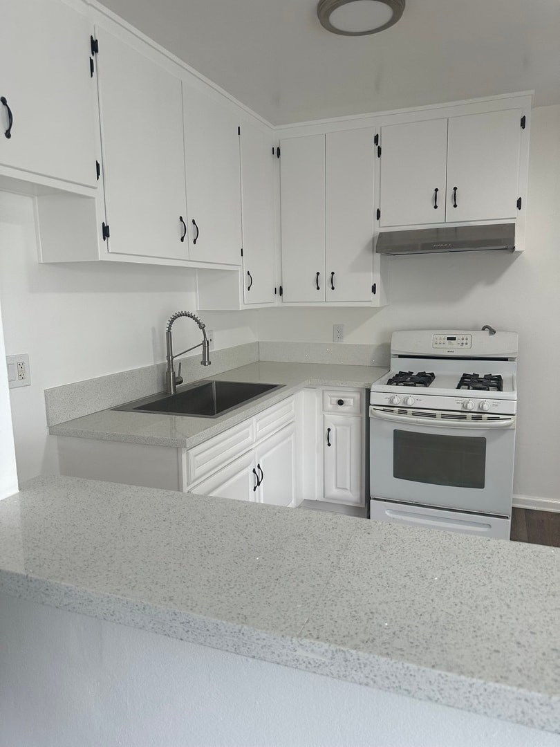 A white kitchen with a sink and stove.