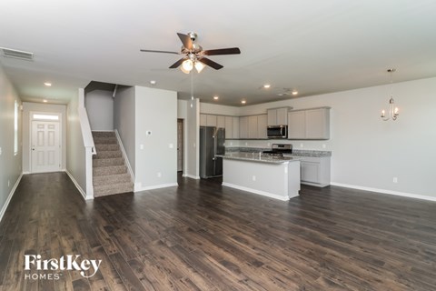 A spacious kitchen and living room with a staircase leading to the upper floor.