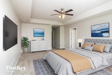 A bedroom with a large bed and a ceiling fan.