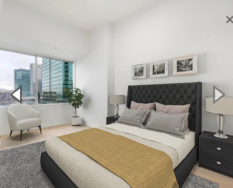 A bedroom with a large bed and a chair by the window.