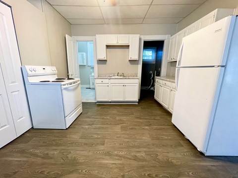 A kitchen with white appliances and wooden floors.