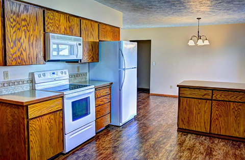 A kitchen with a white refrigerator, white oven, and wooden cabinets.