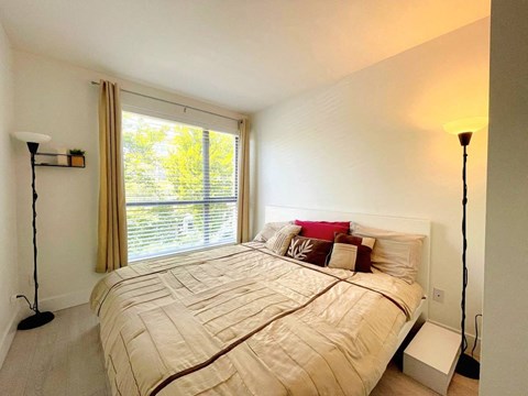 A bedroom with a large bed and a window with curtains.