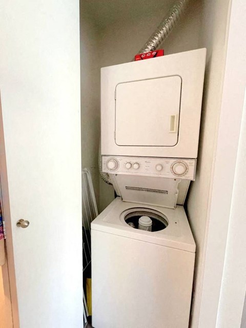 A white washing machine with a red hose attached to it.